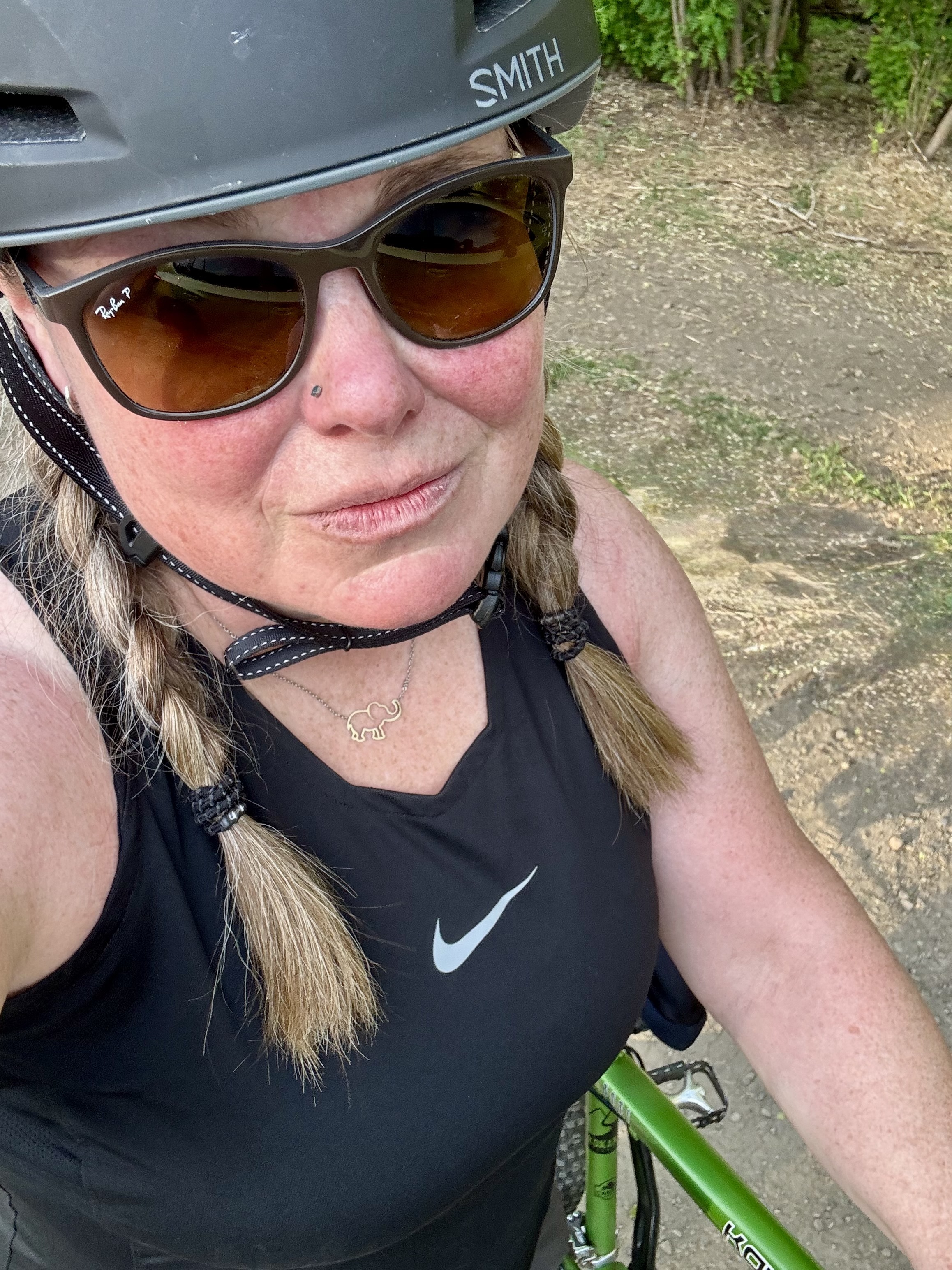 Woman in braids with a black helmet and green mountain bike.
